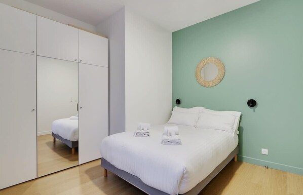 A bedroom with a bed, a wardrobe, and a mirror on the wall. - A Cosy 2-BR in Reuilly-Diderot (Paris)