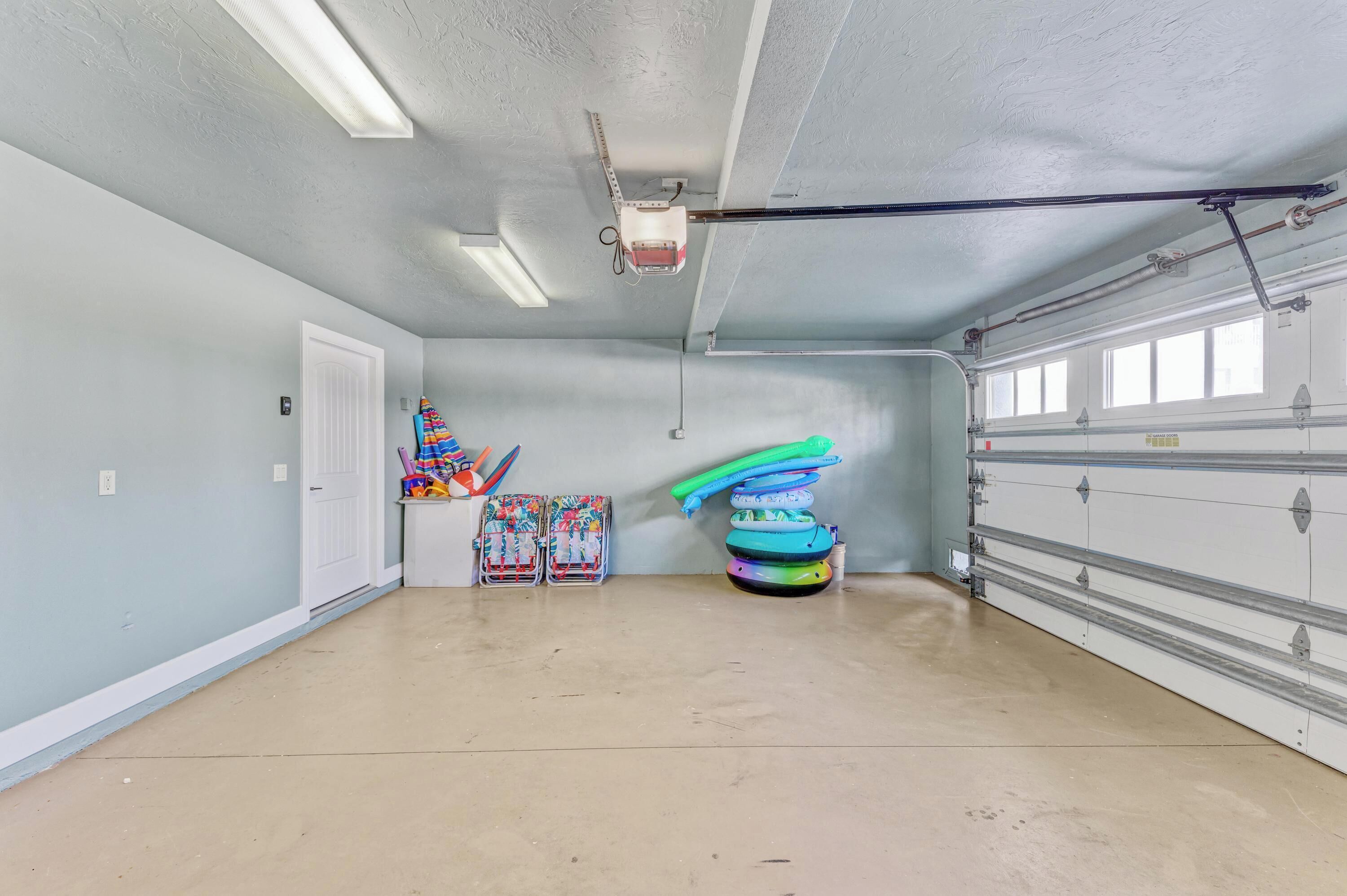 A garage with a concrete floor, a white door, and a ceiling with fluorescent lights.