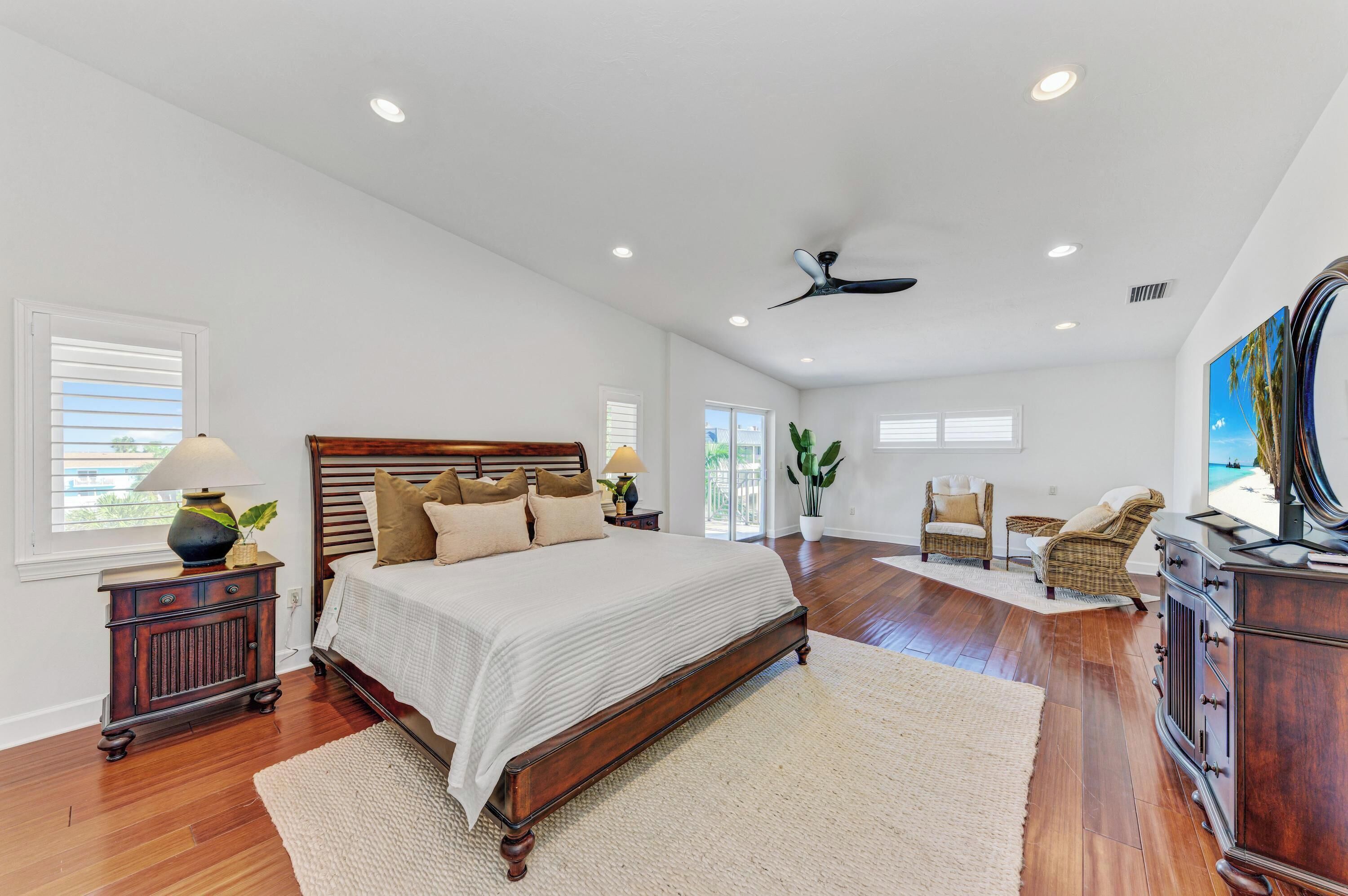 A spacious bedroom with a large bed, wooden headboard, and a ceiling fan.
