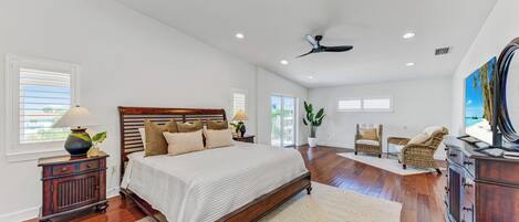 A spacious bedroom with a large bed, wooden headboard, and a ceiling fan.