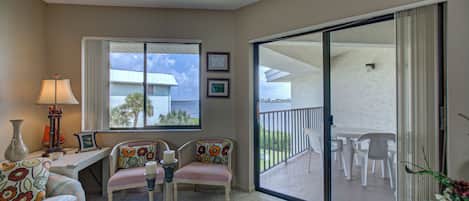 A spacious living area with a sofa, chairs, a coffee table, and a balcony with outdoor seating.