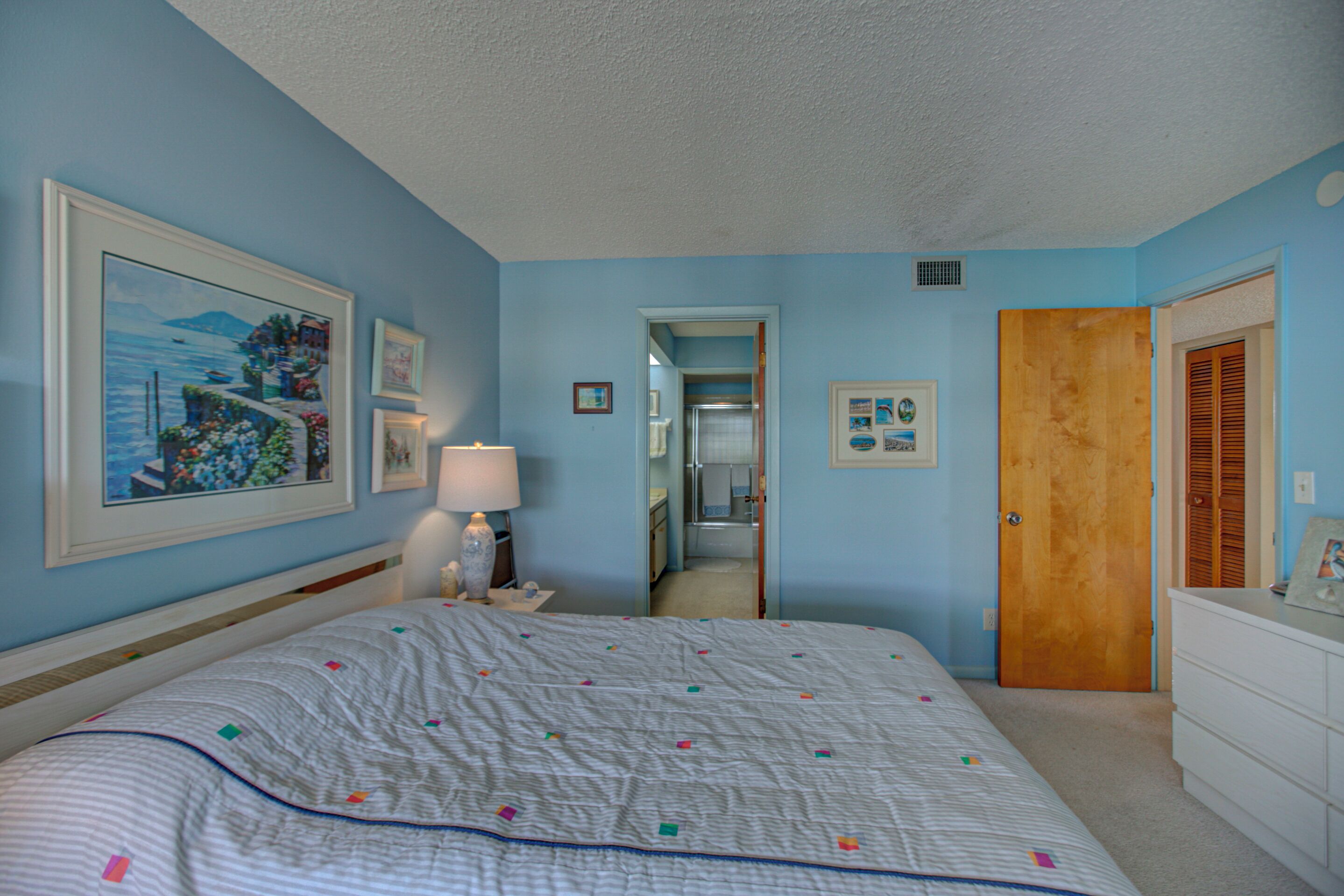 A bedroom with a bed, a dresser, a mirror, and a door.