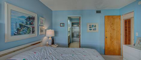 A bedroom with a bed, a dresser, a mirror, and a door.