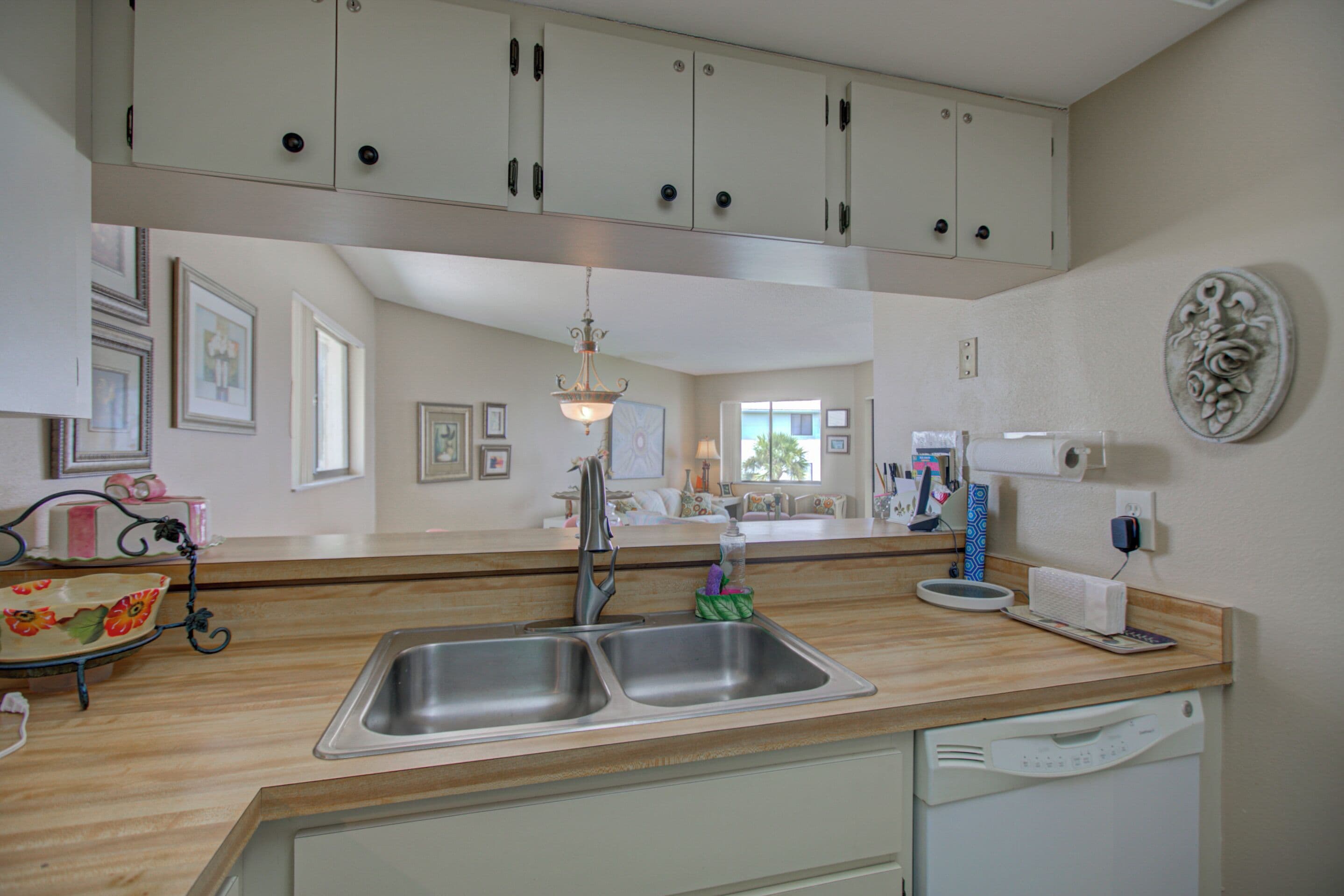 Cucina con lavello doppio, piano di lavoro in legno e pensili bianchi.