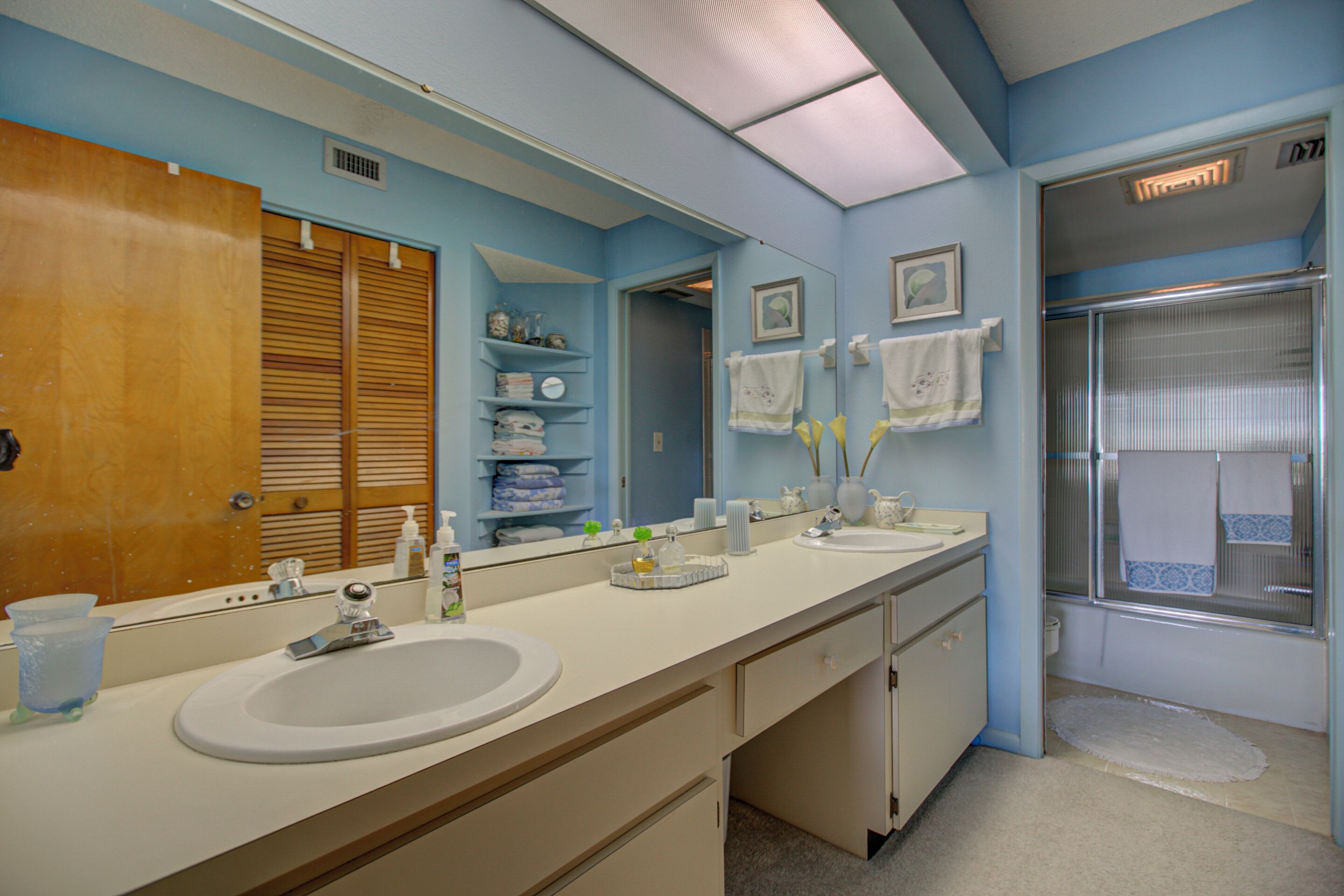 Een badkamer met twee wastafels, een grote spiegel en een douche.