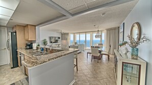 Una cocina moderna con encimeras de granito, una isla central y un comedor con vistas al océano.