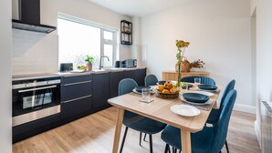 A modern kitchen with dark cabinetry, a built-in oven, and a window above the sink. - Modern Elegant Townhouse in Historic Kenmare (Kenmare)