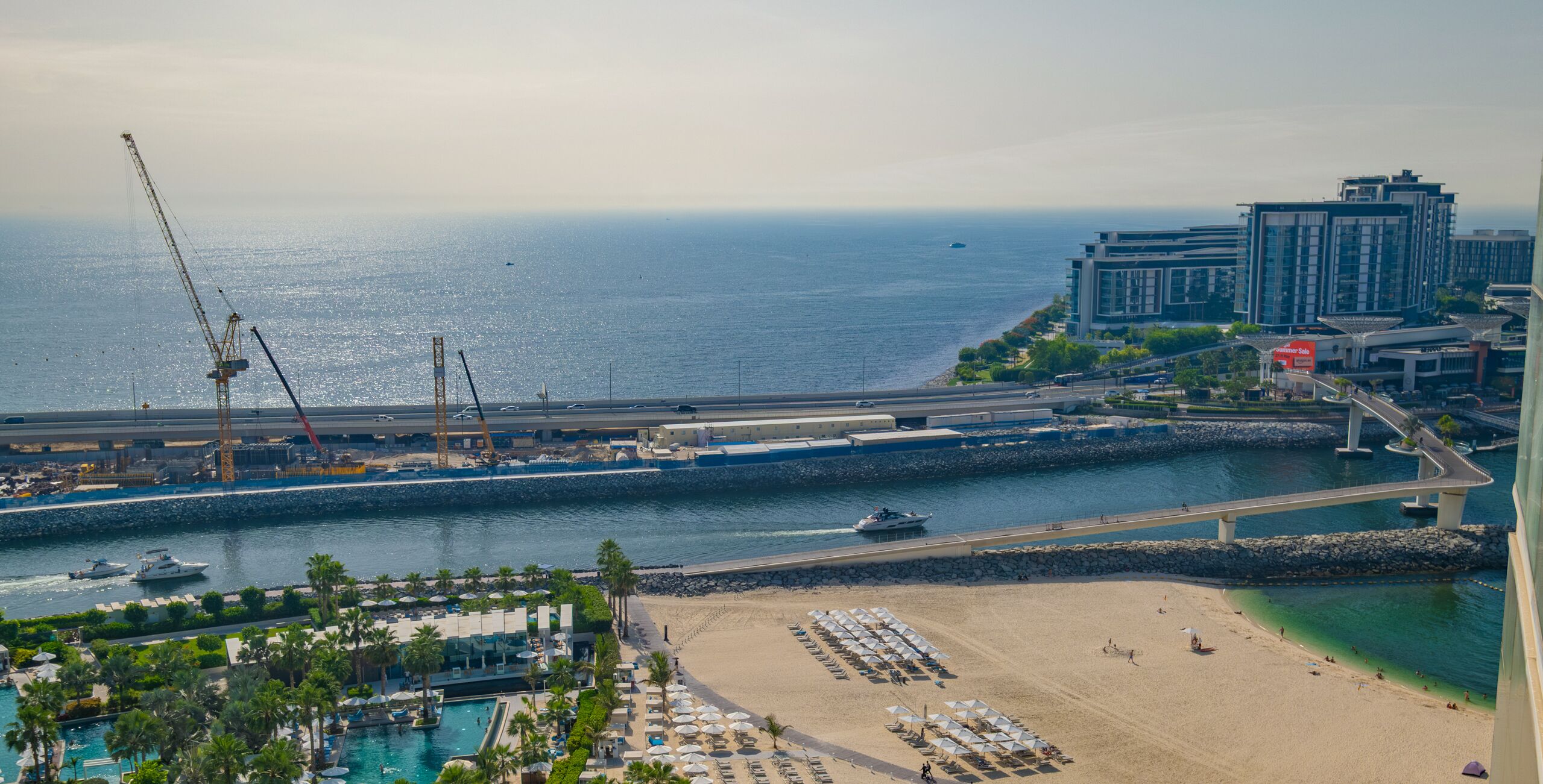 A coastal resort with a beach, a marina, and a large hotel complex.