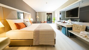 Una habitación de hotel moderna con una cama grande, un escritorio, un televisor y un balcón con vistas al exterior.