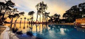 Una piscina que refleja árboles y un atardecer.
