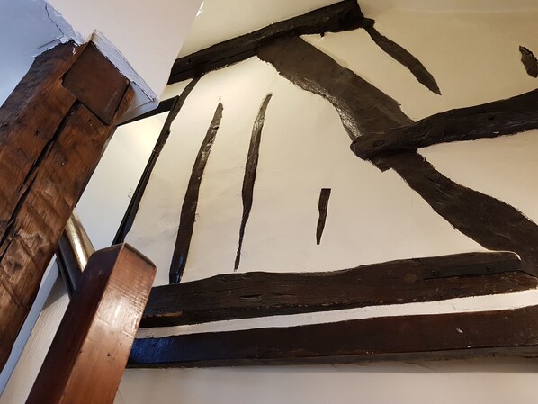 A room with exposed wooden beams and a white ceiling. - Cruck Cottage (Pickering)