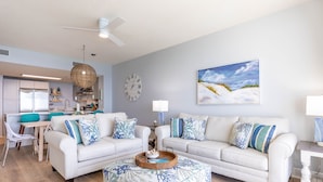 A modern living room with a white sofa, a coffee table, and a dining area with a white table and chairs.