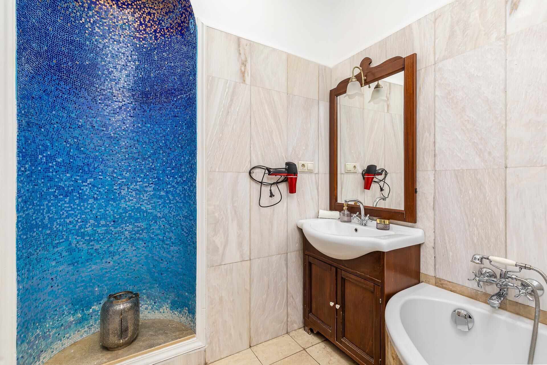 Une salle de bain avec un mur décoré de mosaïques, un lavabo, un miroir et une baignoire.