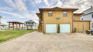 A two-story wooden house with a garage, a covered porch, and a small garden area. - Private Dock, Lanai: Bayou Retreat in Barataria! (Barataria)