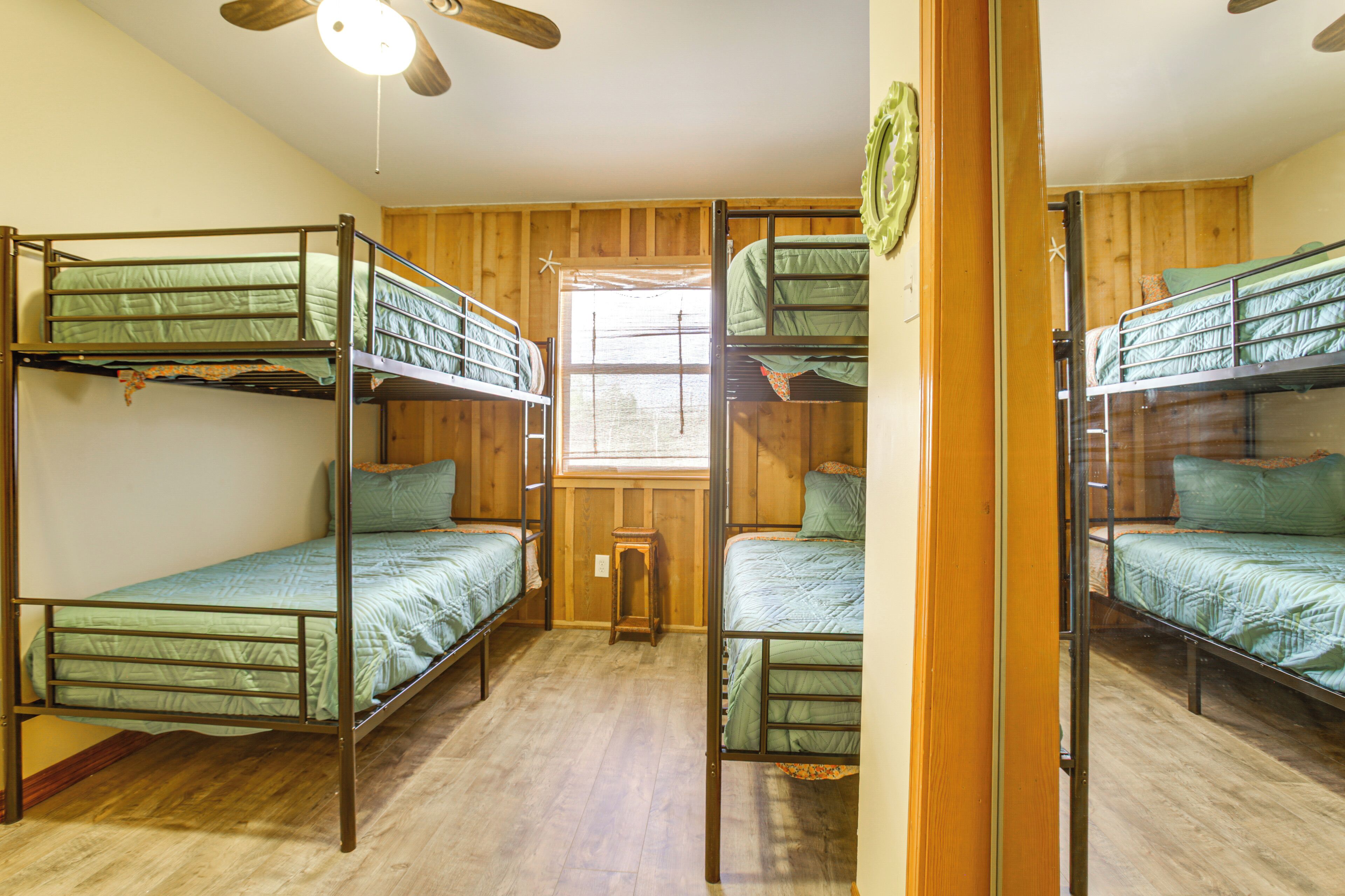 Ein Zimmer mit Etagenbetten, Holzwänden, einem Fenster und einem Deckenventilator.