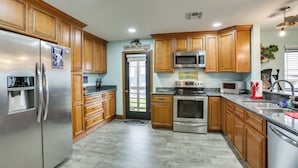 A modern kitchen with wooden cabinets, stainless steel appliances, and a granite countertop. - Private Dock, Lanai: Bayou Retreat in Barataria! (Barataria)