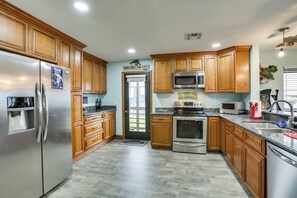 A kitchen with wooden cabinets, stainless steel appliances, and a door with a sign. - Private Dock, Lanai: Bayou Retreat in Barataria! (Barataria)
