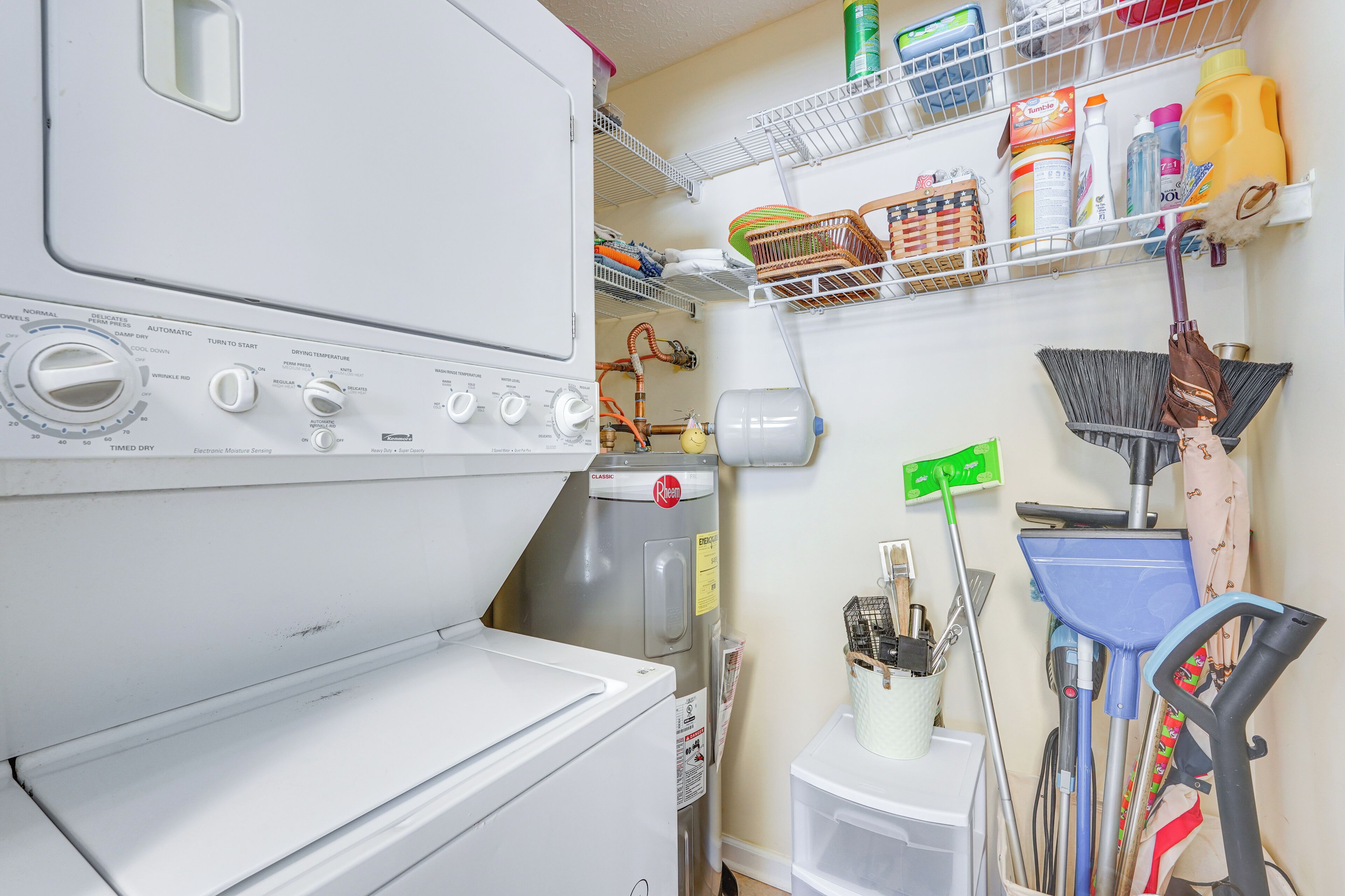 A laundry area with a washing machine, a dryer, and shelves with cleaning supplies.