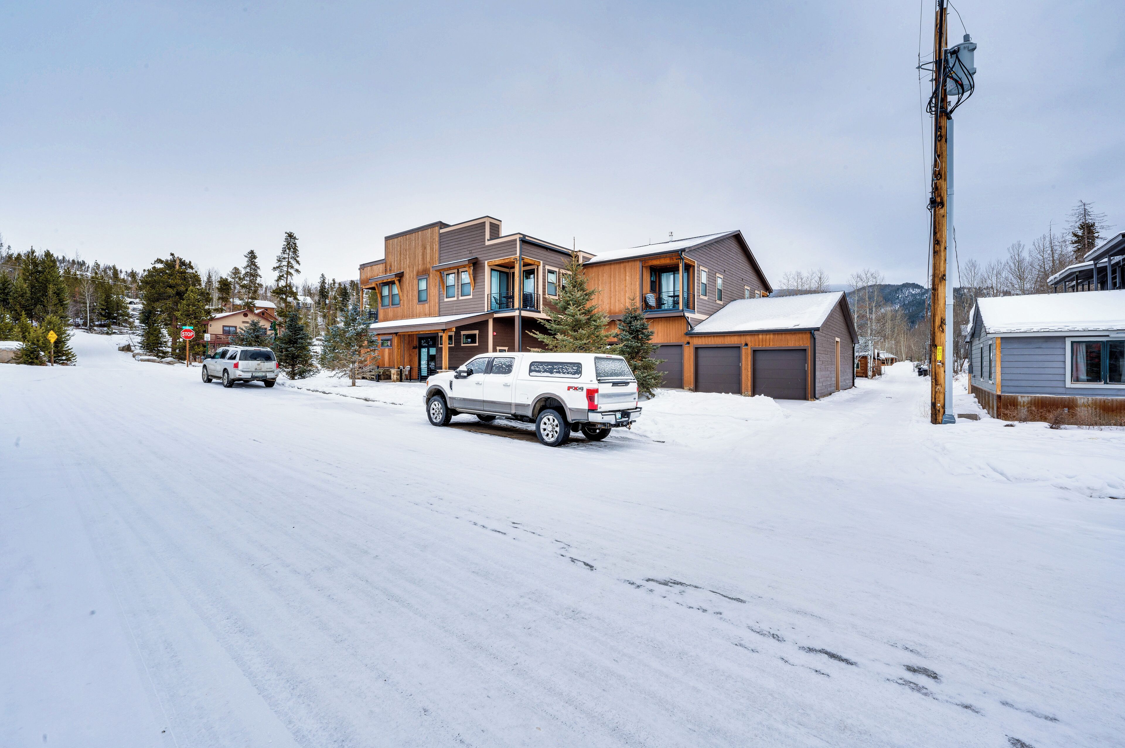 Una calle residencial con casas, una señal de parada y una carretera cubierta de nieve.