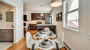 A modern kitchen with a dining area, featuring a glass table, grey plates, and a large window with a city view. - 2 Mi to Rmnp: Mtn-view Grand Lake Loft! (Grand Lake)