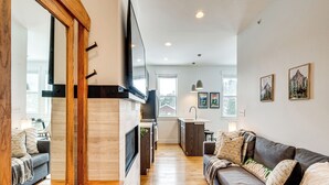 A modern kitchen with a large TV, wooden cabinets, and a built-in oven. - 2 Mi to Rmnp: Mtn-view Grand Lake Loft! (Grand Lake)