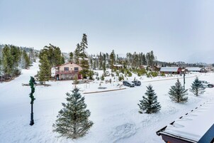 Un paisaje nevado con un albergue, varios coches y árboles de hoja perenne.