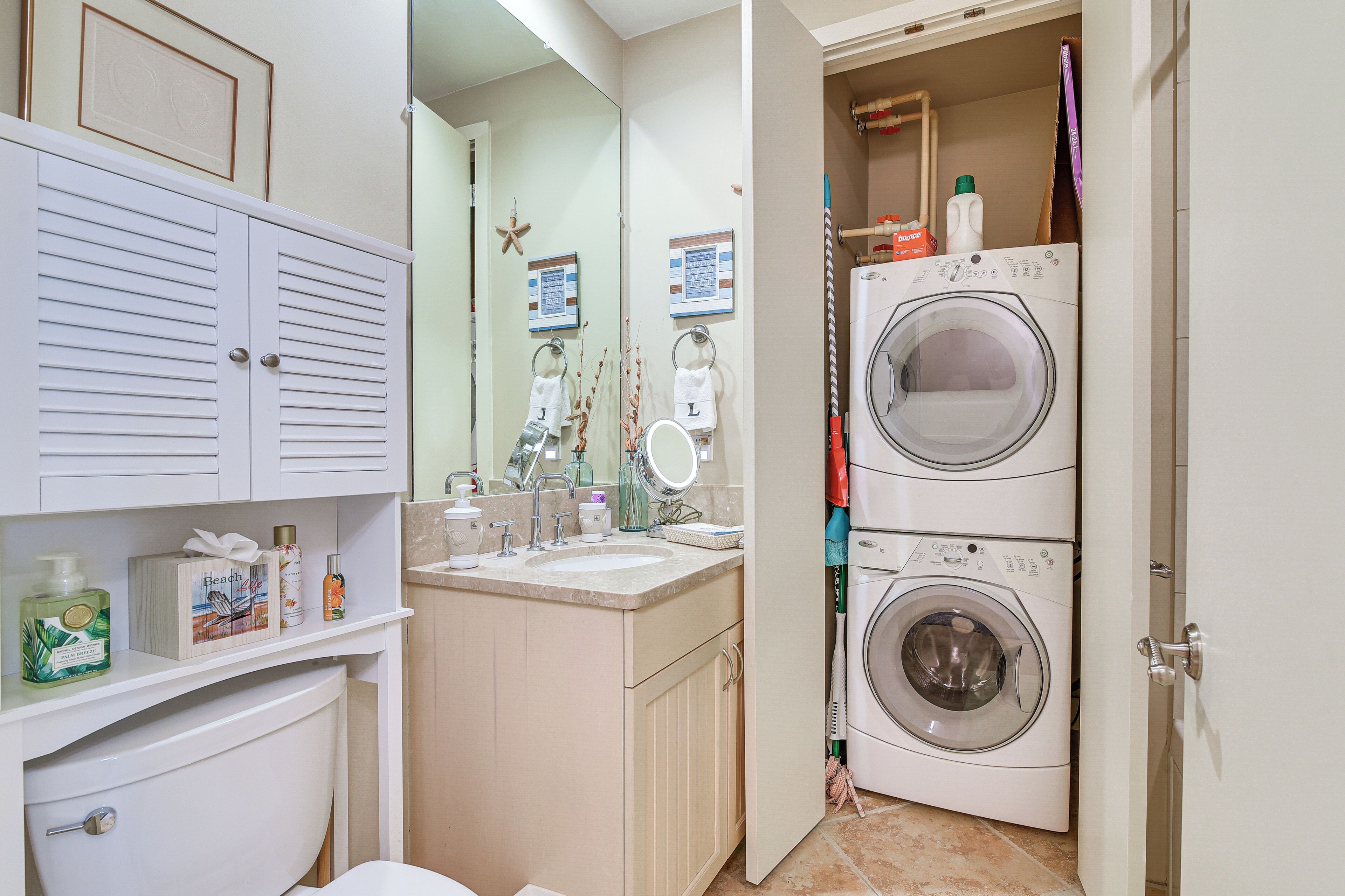 A compact bathroom with a toilet, sink, and stacked washer-dryer unit.