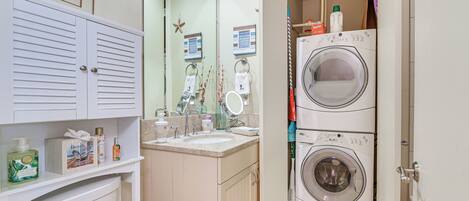 A compact bathroom with a toilet, sink, and stacked washer-dryer unit.