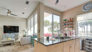 A modern kitchen with a large island, a dining area with a sofa, and a TV in the living room.