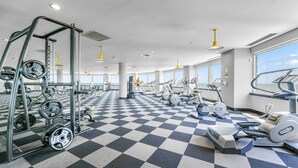 A gym with various exercise equipment, a checkered floor, and large windows.