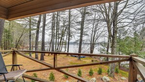 A wooden deck with a view of a lake and trees.