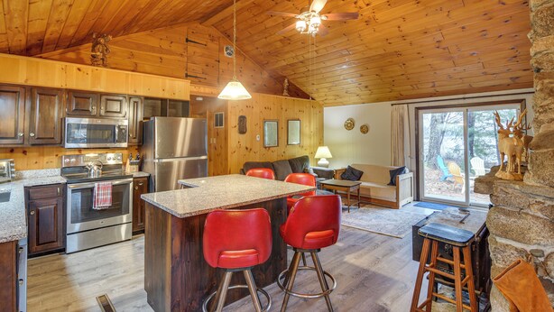 A wooden cabin interior with a kitchen, bar area, and seating space.