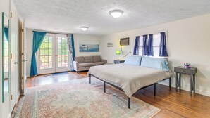 A bedroom with a bed, a sofa, a rug, and a nightstand. - Adorable Cottage: Fire Pit, Walk to Colonial Beach (Colonial Beach)