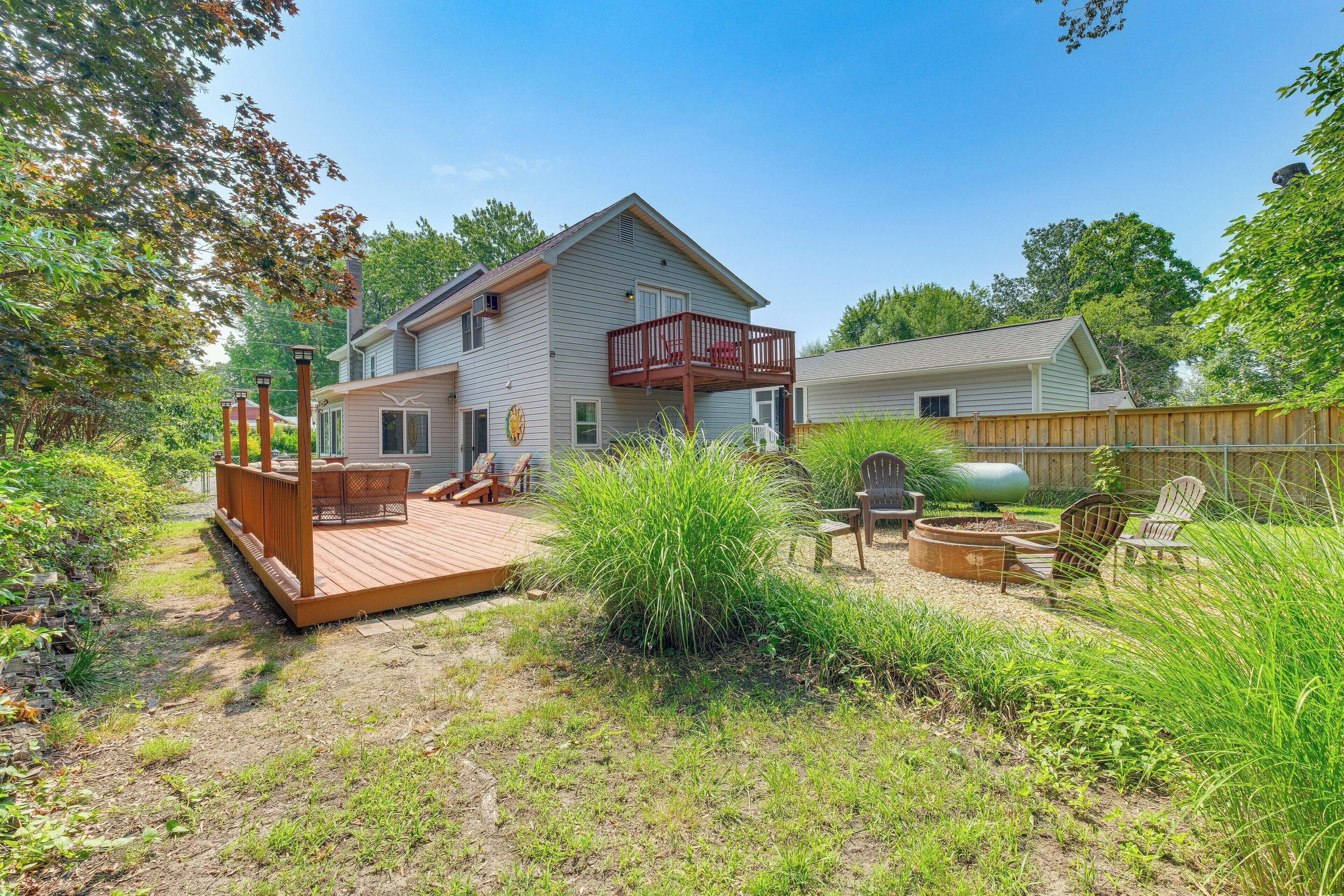 A two-story house with a deck, outdoor seating, and a fire pit.