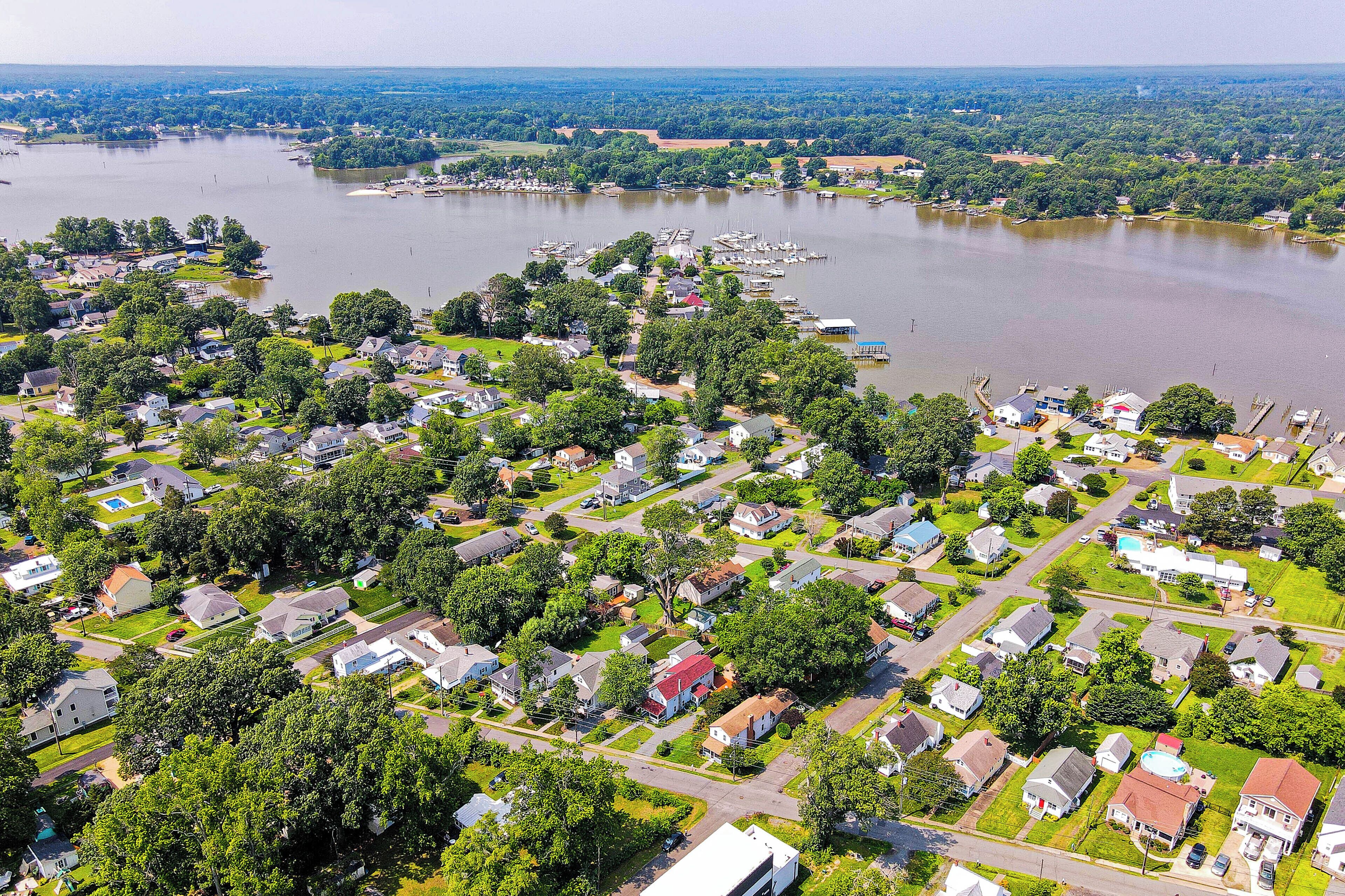 Vue aérienne d’un quartier résidentiel avec des maisons, un port de plaisance et une vaste étendue d’eau.