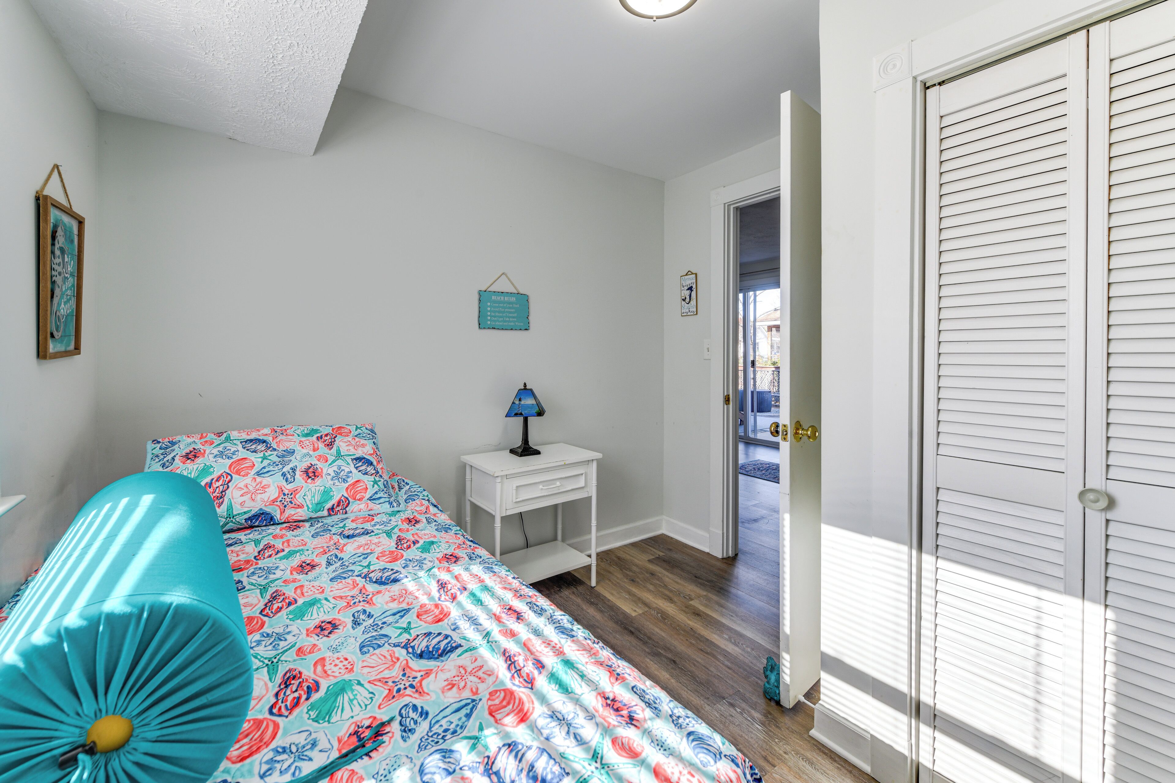 A bedroom with a bed, a nightstand, a lamp, and a door leading to a balcony.