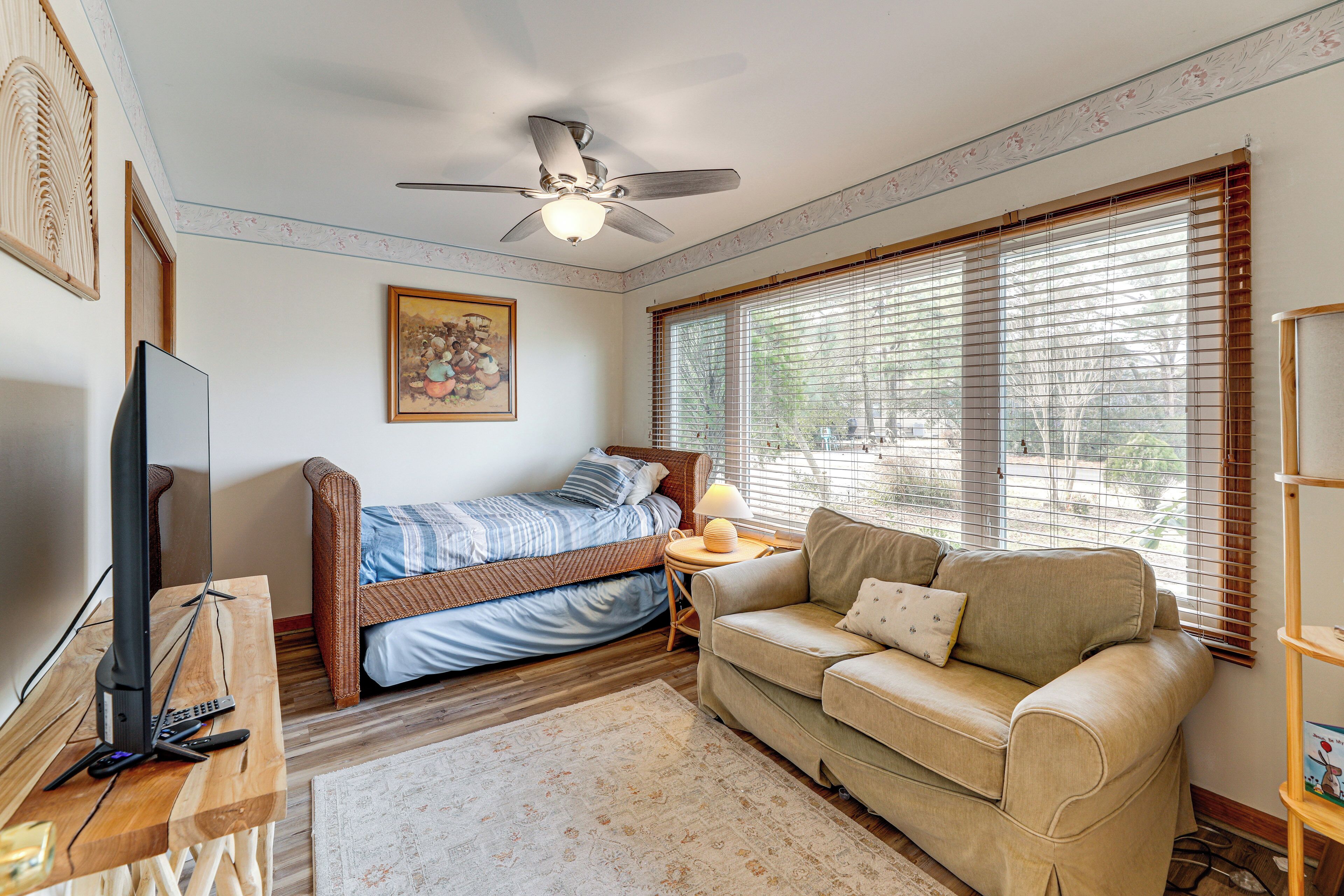 A bedroom with a bed, a sofa, a TV, and a ceiling fan.