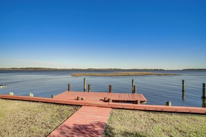 A wooden dock extending into calm water with a clear sky above.
