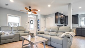 A spacious living room with two grey sofas, a wooden coffee table, and a ceiling fan.