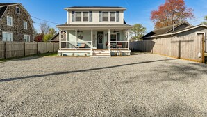 A two-story house with a front porch, a gravel driveway, and a wooden fence.