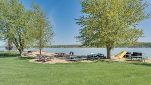 A lakeside park with picnic tables, benches, and a playground.