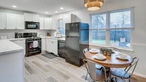 A modern kitchen with white cabinets, stainless steel appliances, and a dining area with a wooden table and chairs.