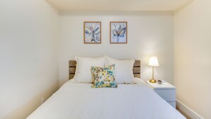 A neatly made bed with white linens, a floral pillow, and two framed floral paintings on the wall. - Modern Lehi Apartment: 2 Mi to Thanksgiving Point (Lehi)