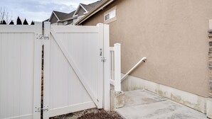 A gated entrance with a white gate, a concrete step, and a beige wall. - Modern Lehi Apartment: 2 Mi to Thanksgiving Point (Lehi)