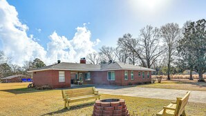 A brick building with a front porch, a fire pit, and two wooden benches.