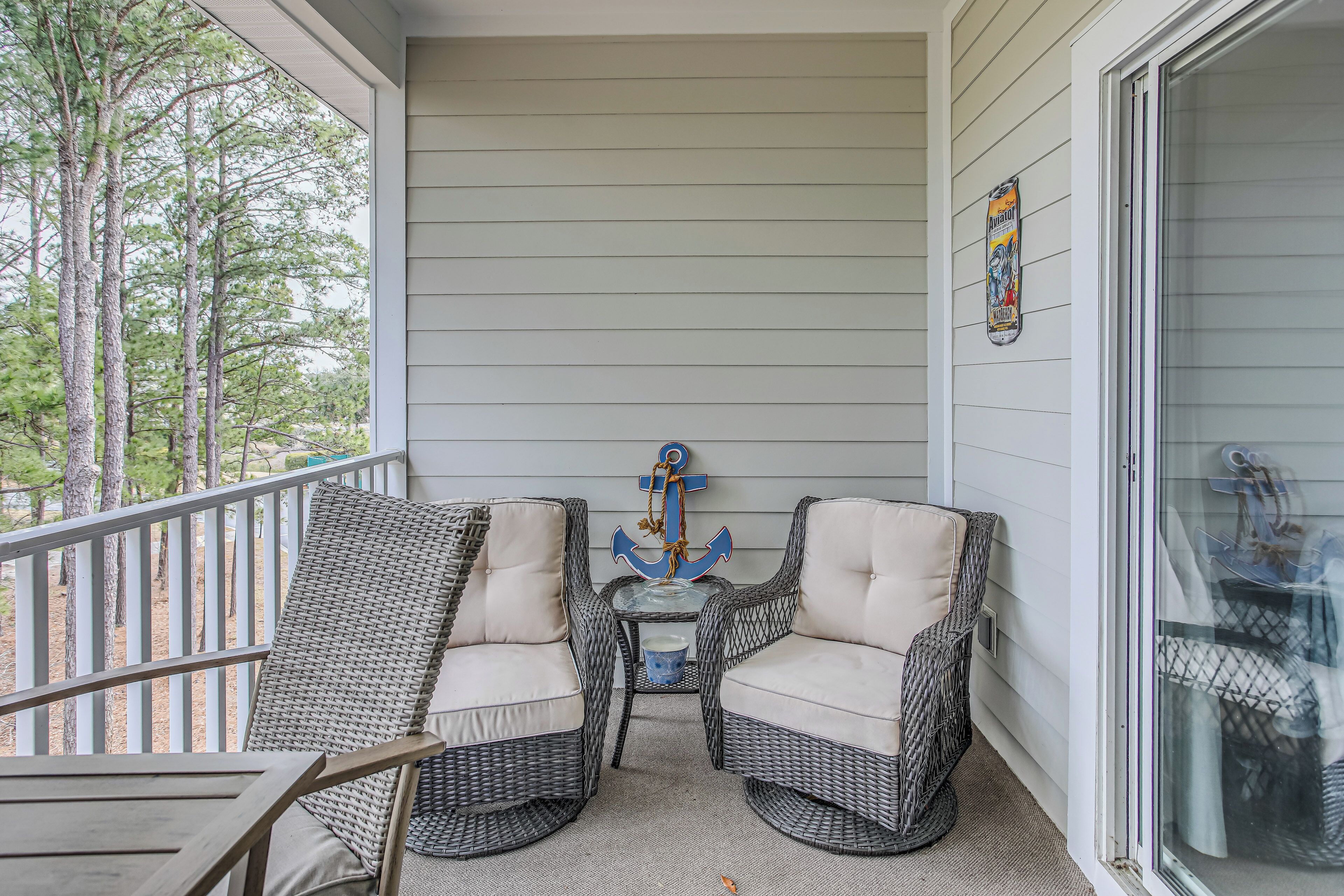 A porch with wicker chairs, a small table, and a decorative anchor.