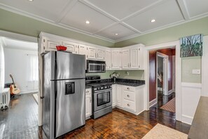 A kitchen with white cabinets, stainless steel appliances, and a wooden floor. - Charming Connecticut Retreat Near Museums & Hiking (Waterbury)