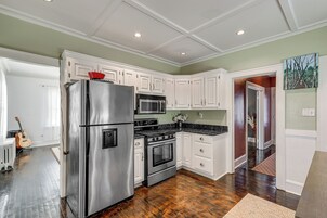 Una cocina con armarios blancos, electrodomésticos de acero inoxidable y suelo de madera.