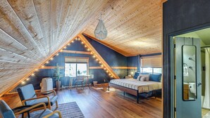 A cozy attic bedroom with a sloped ceiling, wooden beams, a bed, a desk, and a chair. - Munds Park Cabin w/ Deck & Fire Pit: Walk to Trail (Munds Park)