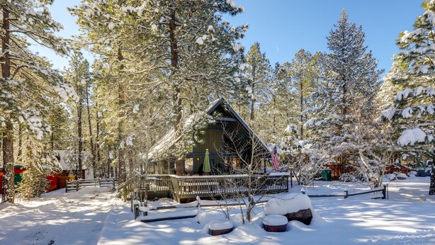 A cabin surrounded by snow-covered trees, with a clear sky above. - Munds Park Cabin w/ Deck & Fire Pit: Walk to Trail (Munds Park)